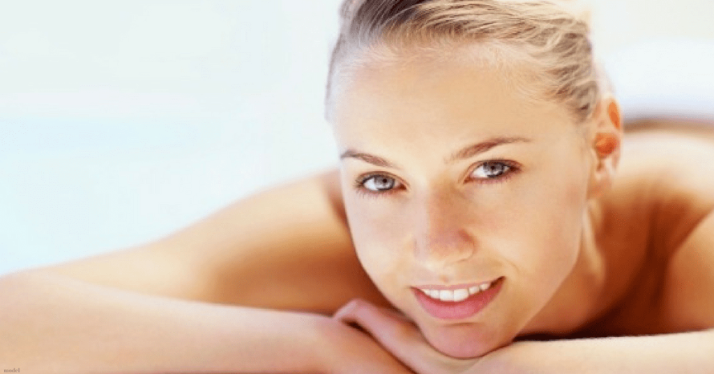 Fresh faced young woman lying down with face resting on crossed arms