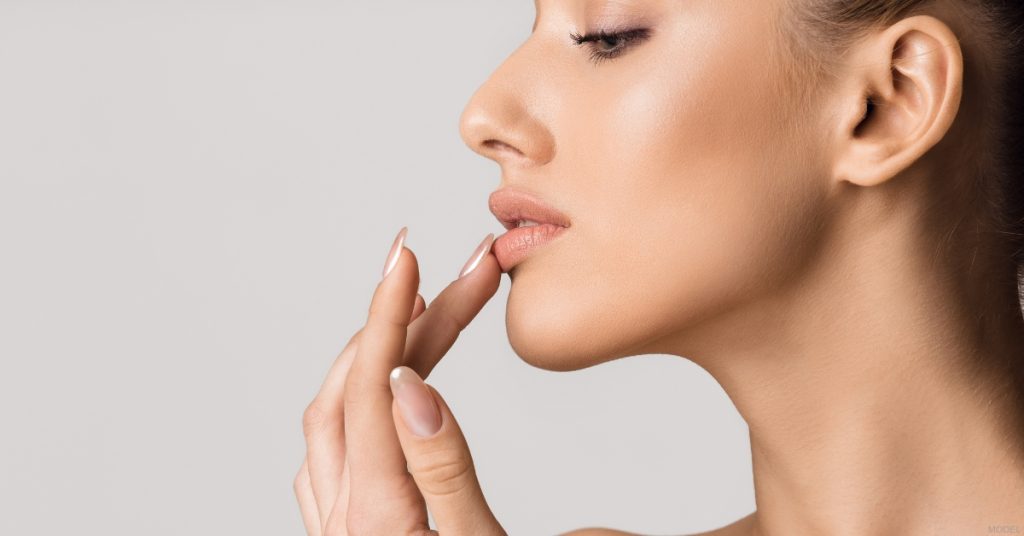 Woman gently touching her lips. (MODEL)